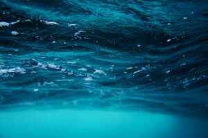 Serene underwater view of sea surface with vibrant turquoise and blue waves.